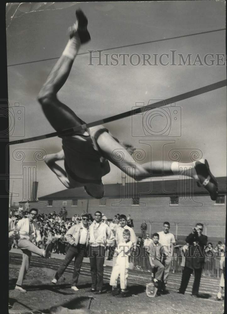 1961 Press Photo Bill Holden jumps over bar, invitational track meet, Wisconsin. - Historic Images