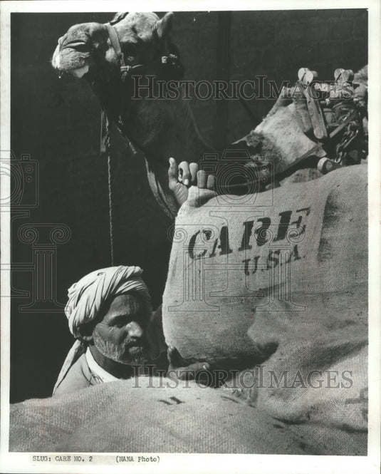 1972 Press Photo Indian lifting CARE package on his camel's back in India-Historic Images