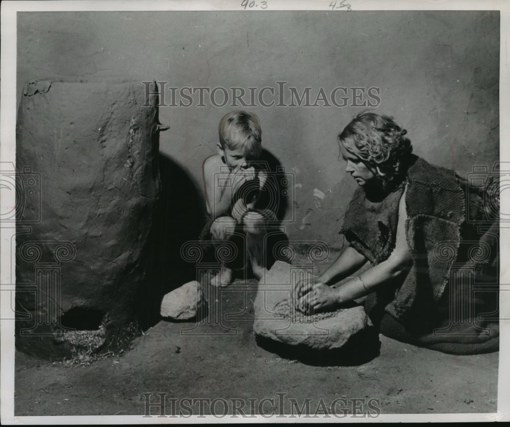 1953 Press Photo Iron Age Mother Grinding Grain For Bread With Her Child-Historic Images