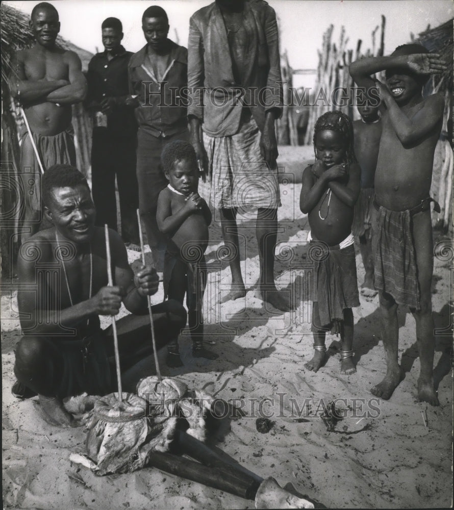 1963 Press Photo Bushman using a mill for grinding while villagers wat ...