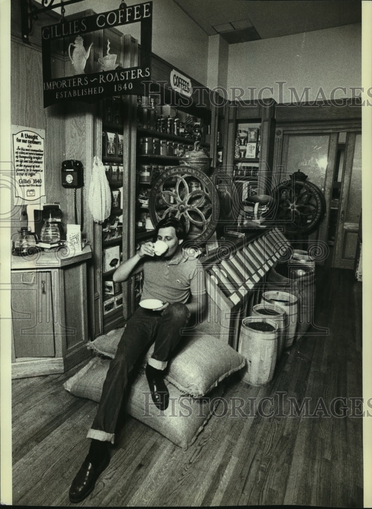 1979 Donald Schoenholt sipped coffee as he sat on two sacks of it - Historic Images