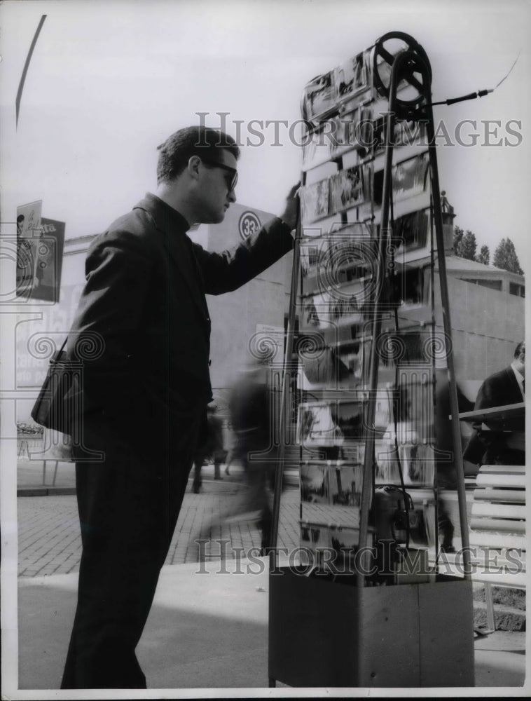 1961 Press Photo Looking through postcards on a motor powered rack in Italy-Historic Images