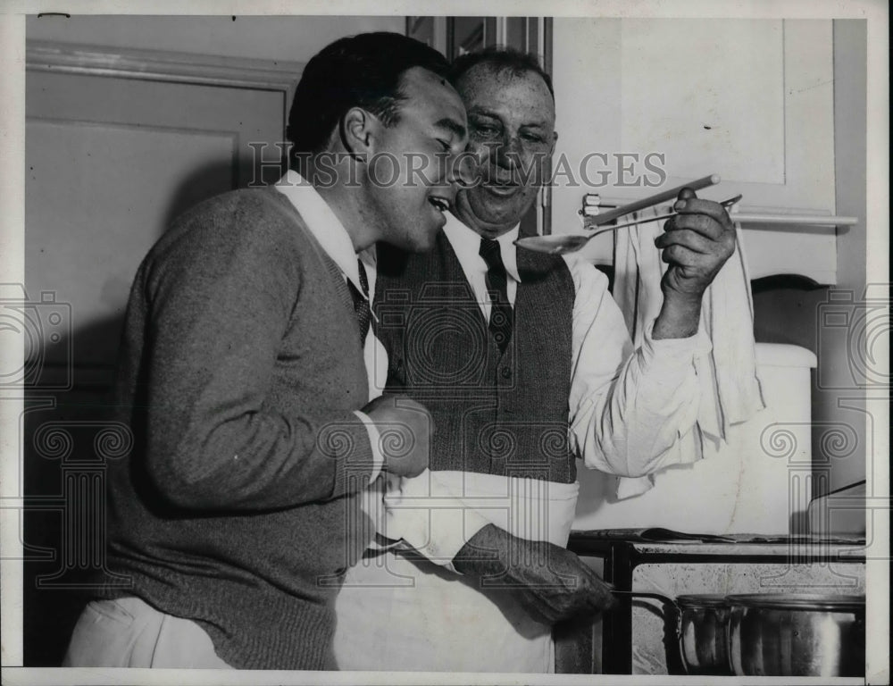 1933 Jim McLarnier and John Foster sample food in a kitchen - Historic Images