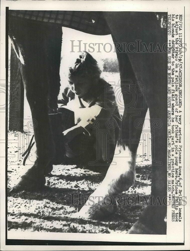 1957 Princess Anne adjusts straps on father's pole pony - Historic Images