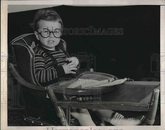 1939 A child in his high chair in talk of child income tax - Historic Images