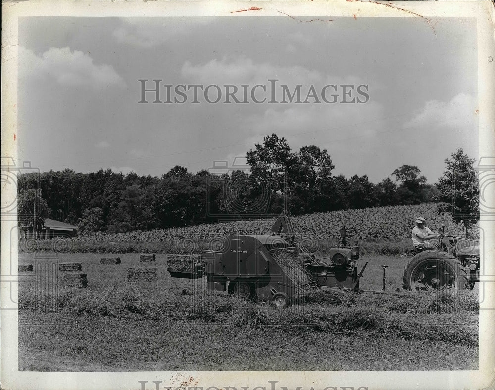 1950 A baling machine at work in a hay field  - Historic Images