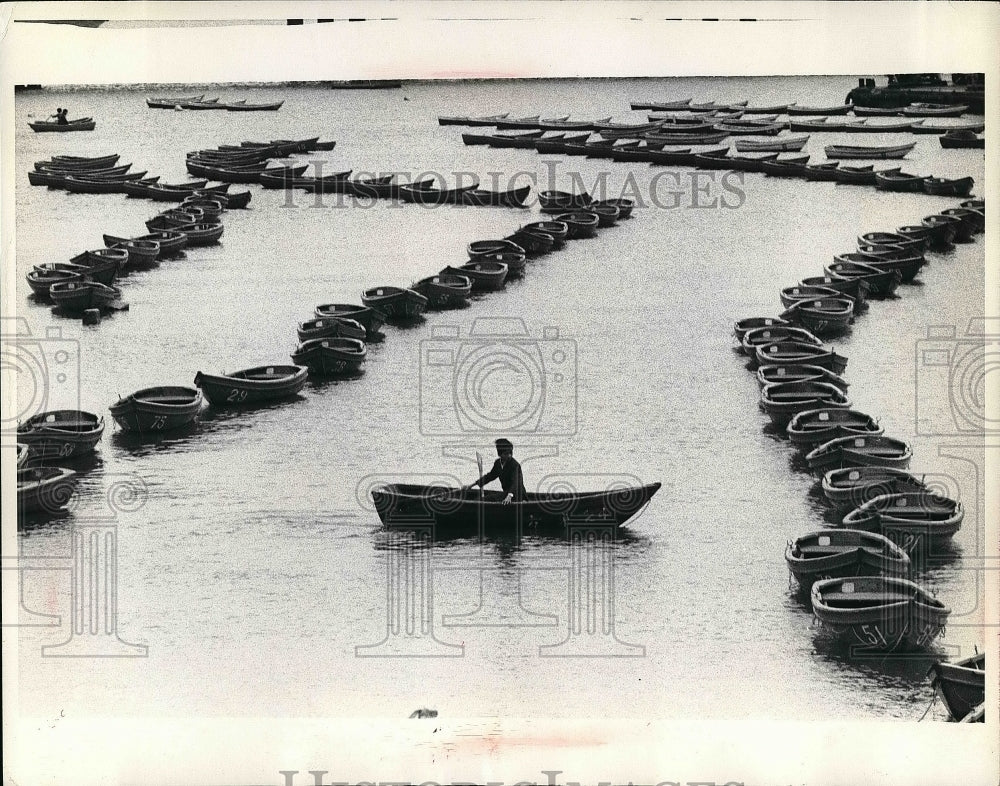 Man on a boat in between lines of boats  - Historic Images