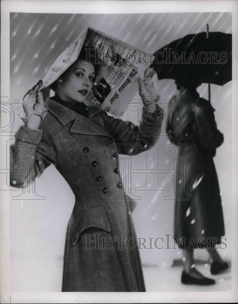 1942 Press Photo Woman in snow with newspaper over her head - nea60186 - Historic Images
