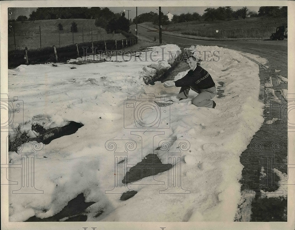 1947 Press Photo man displaying snow along a road in Cleveland - Historic Images