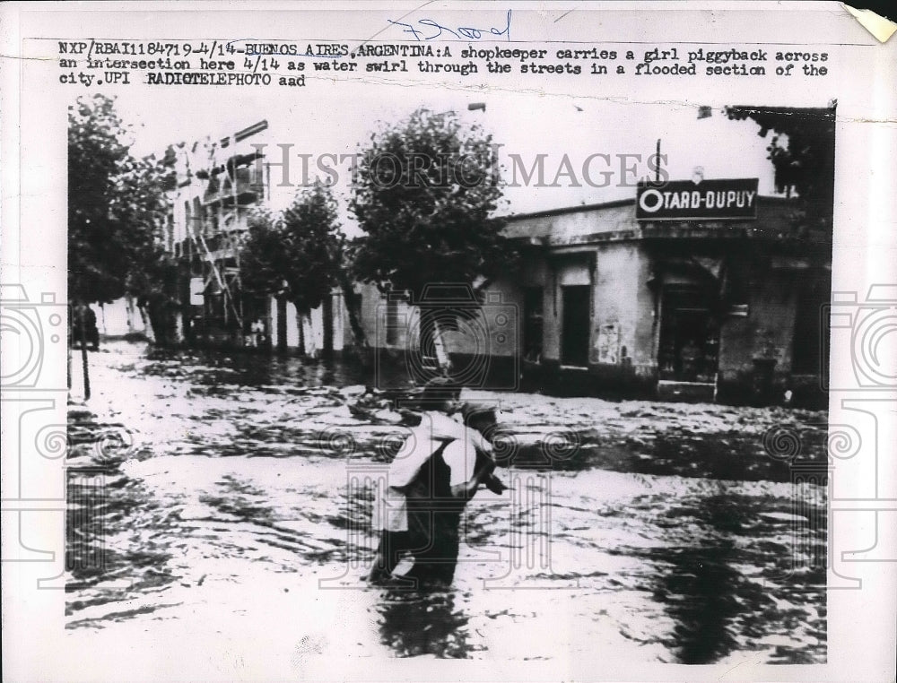1959 Shopkeeper Carries Girl Across Flooded Street In Buenos Aires - Historic Images