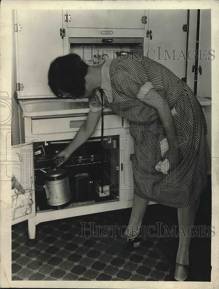 1926 Woman pulling kerosene lamp out of cabinet  - Historic Images