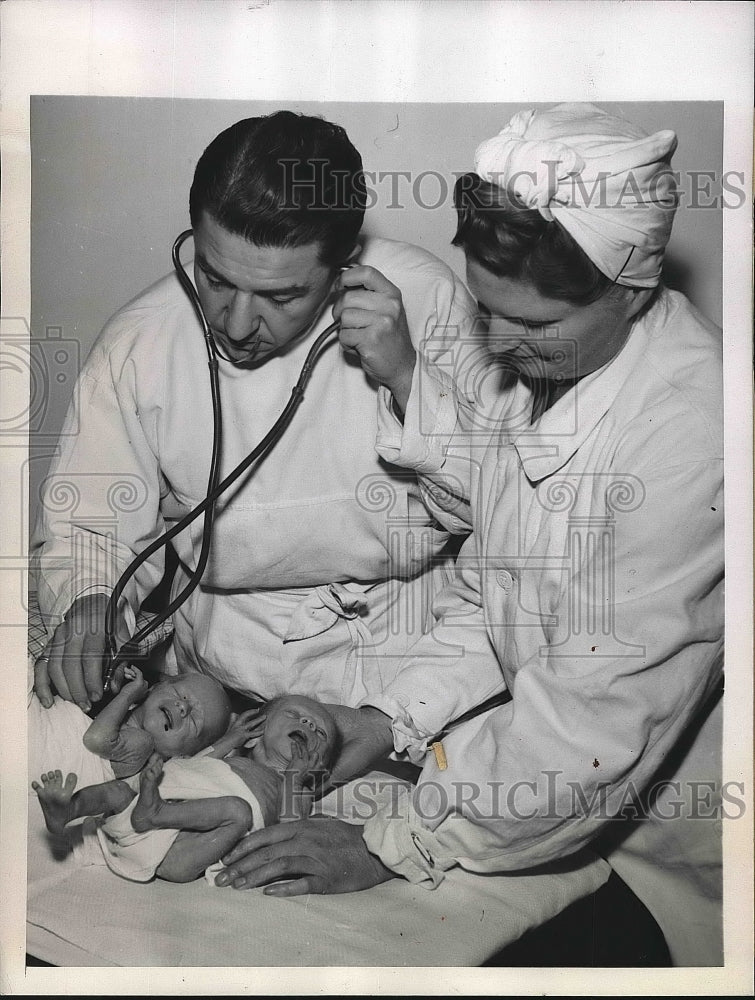 1945 Dr. Gerard assisted by nurse checking condition of babies - Historic Images