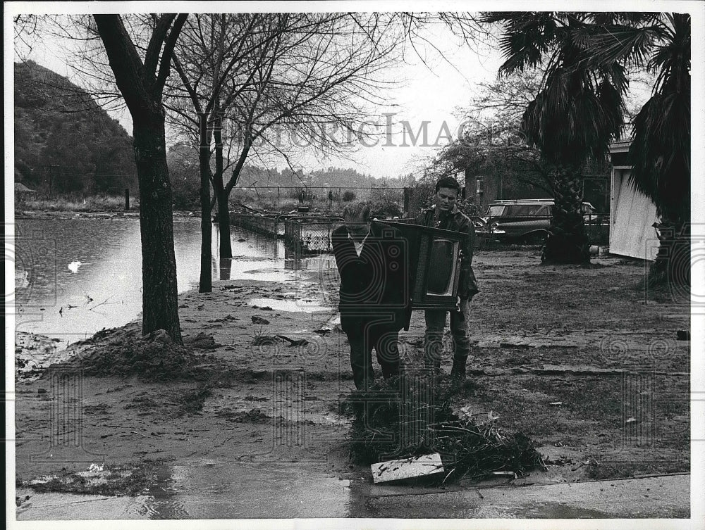 1969 Press Photo Ed Heddy &amp; Al Pinaro carry TV above flooding in Sunland, Calif. - Historic Images