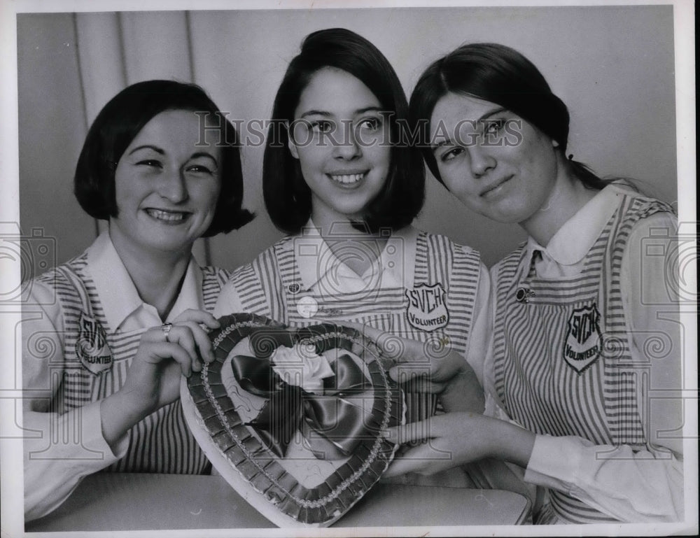 1967 Three Ladies Volunteers of SVCH holds a heart shape object. - Historic Images