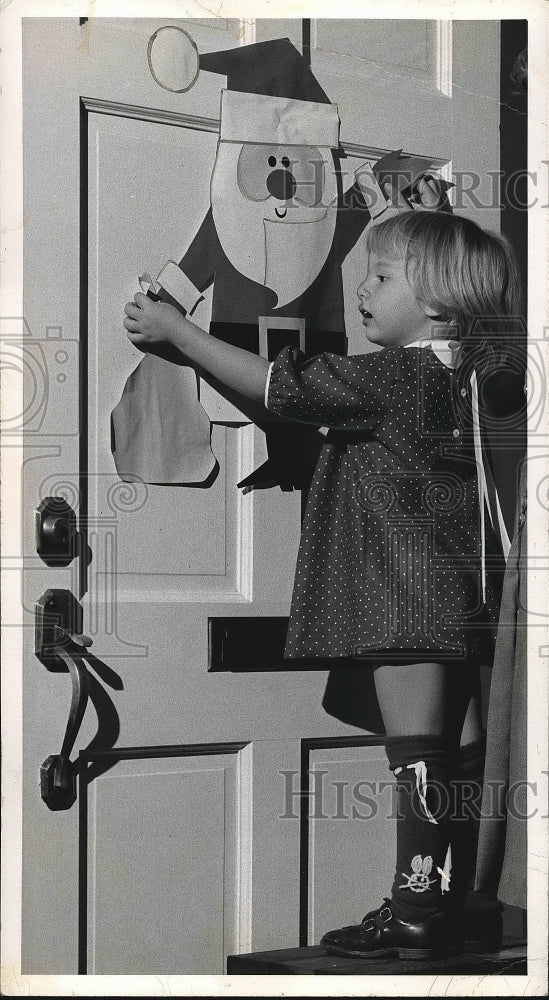 1966 Press Photo Little Girl Decorating a Door with Santa Clause - nea71223 - Historic Images