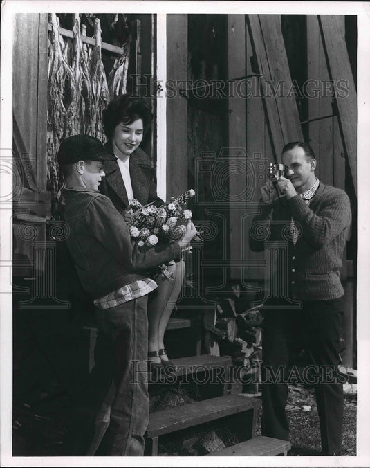 1965 A man photographing a boy & woman with load of corn  - Historic Images