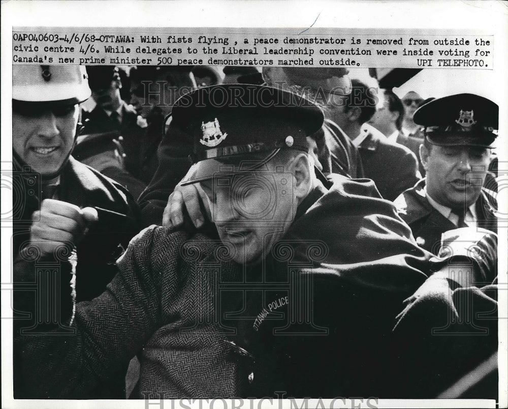1968 A demonstrator being held back by officer  - Historic Images
