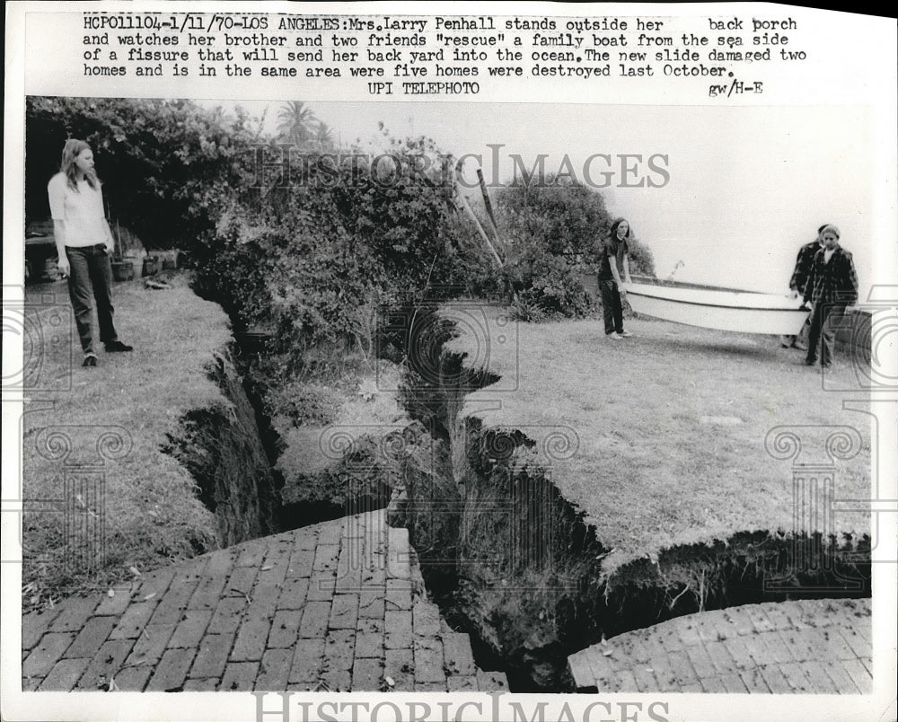 1970 Mrs Larry Penhall standing next to a fissure in her backyard - Historic Images