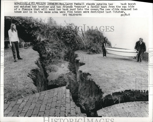 1970 Mrs Larry Penhall standing next to a fissure in her backyard - Historic Images
