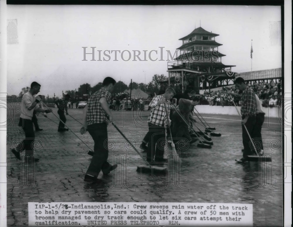 1956 Crew sweeps rain water off the track to help dry pavement so - Historic Images