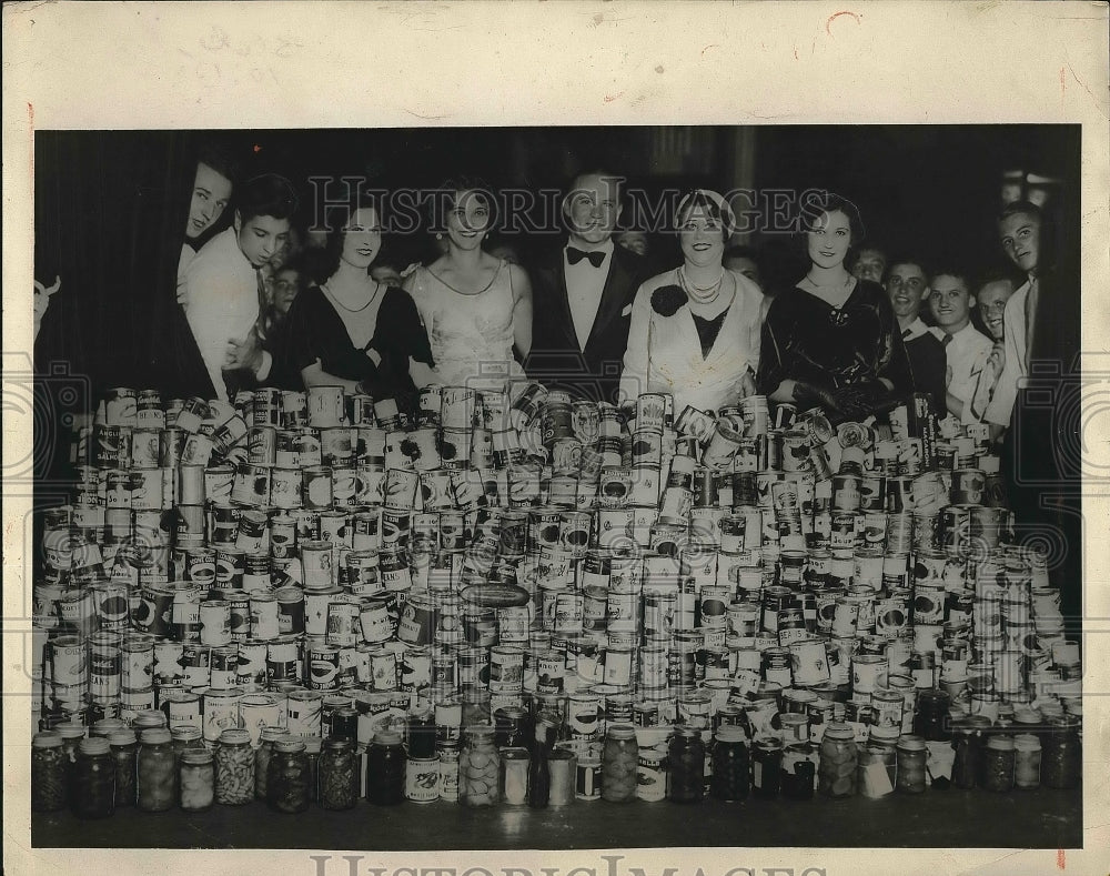 1931 Socialites Standing with Pile of Canned Food  - Historic Images