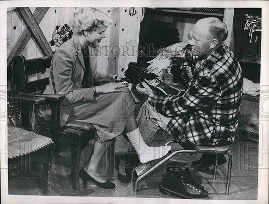 1952 salesman helping lady buy ski boots  - Historic Images