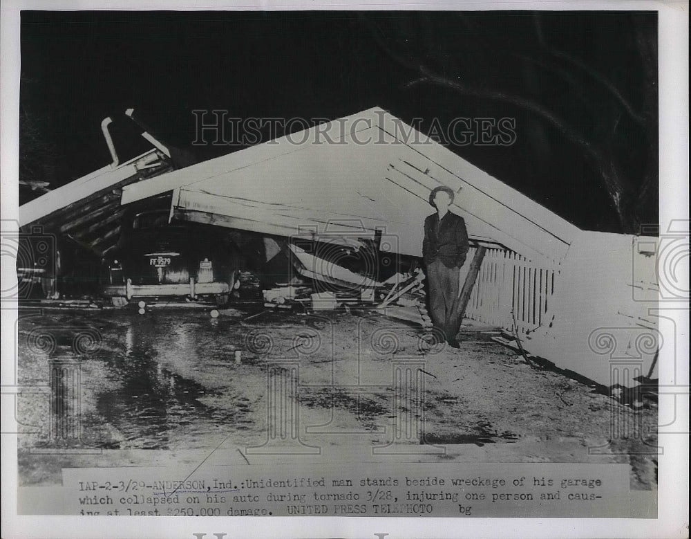 1929 Man stands next to wreckage of garage and car after tornado - Historic Images