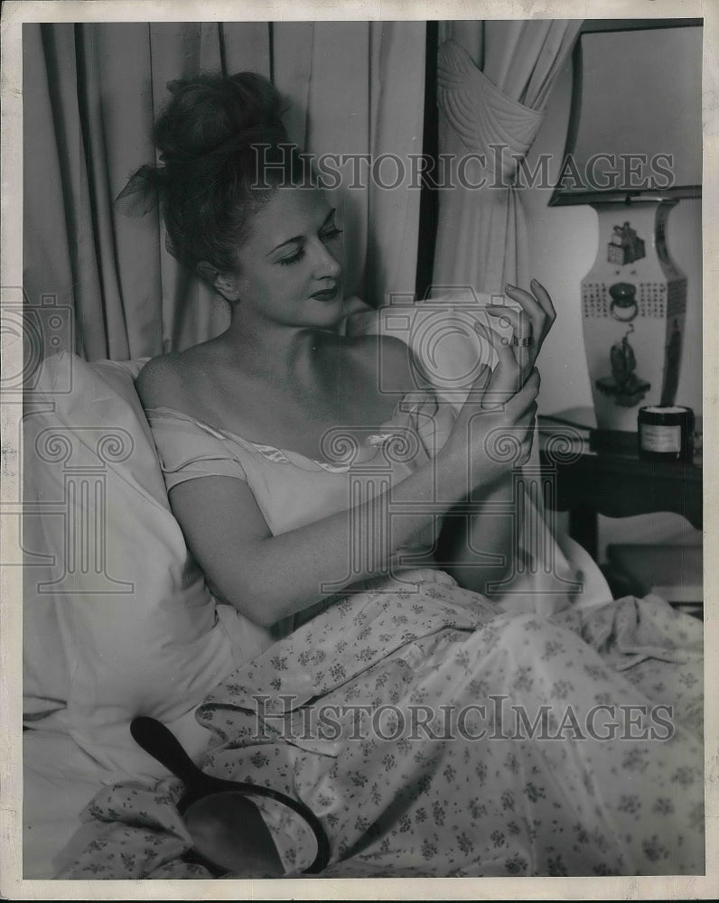 Housewife Putting Lotion On Her Hands At Bedtime  - Historic Images