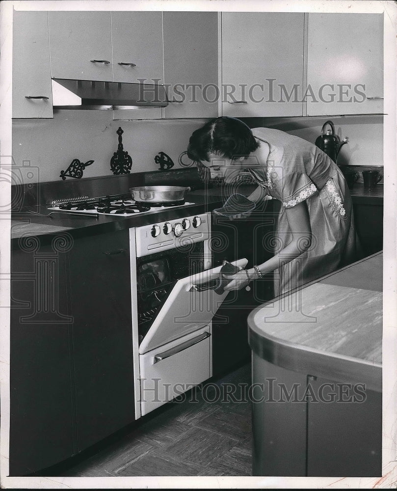 1954 A homemaker checkin food in her kitchen oven  - Historic Images