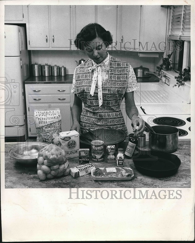 1957 A homemaker in her kitchen ready to cook  - Historic Images