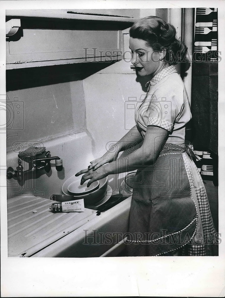 1955 A homemaker using new cream on hands to wash dishes  - Historic Images