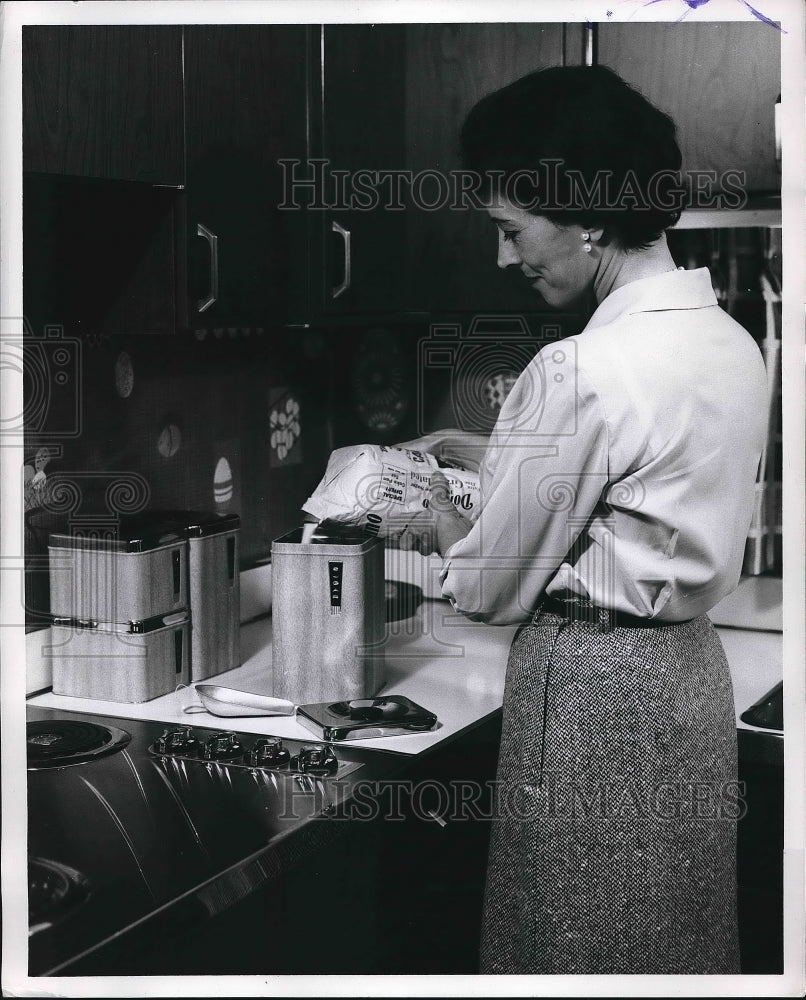1962 Woman pouring sugar in kitchen canister  - Historic Images