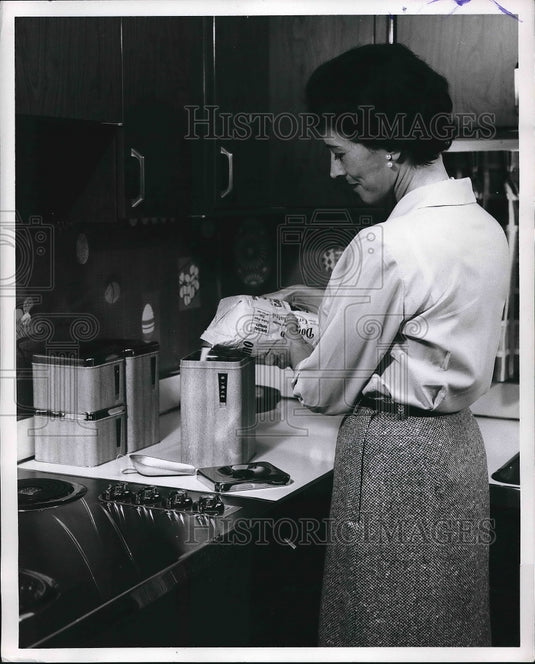 1962 Woman pouring sugar in kitchen canister  - Historic Images