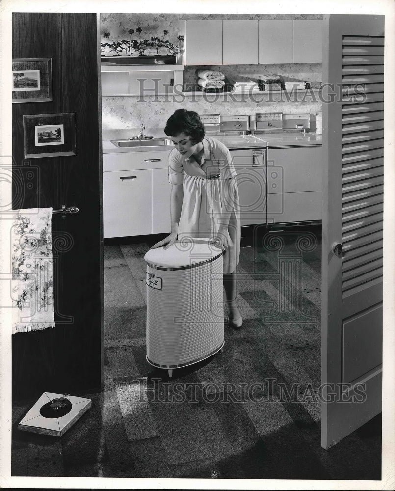 1961 the woman pushing a container through the kitchen  - Historic Images