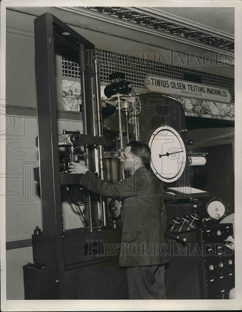 1935 A man using a metal strength testing machine  - Historic Images