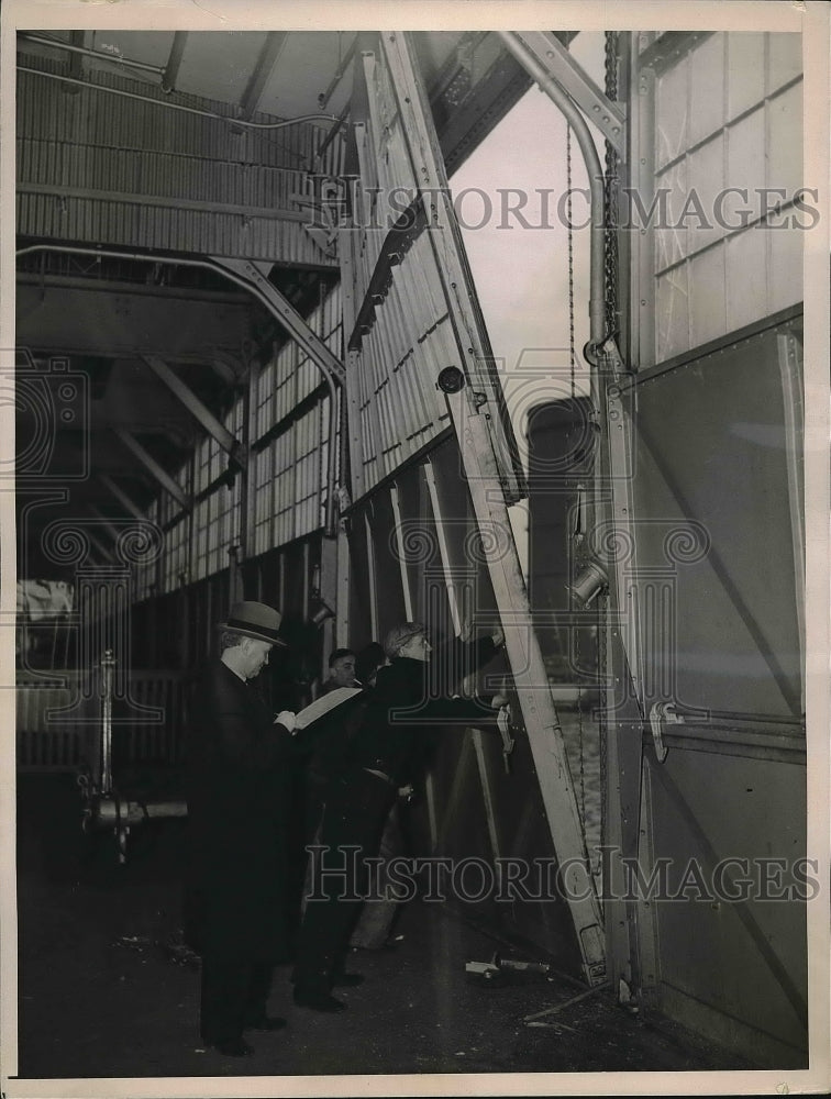 1937 Workmen, Steamship official trying to push back steel door - Historic Images