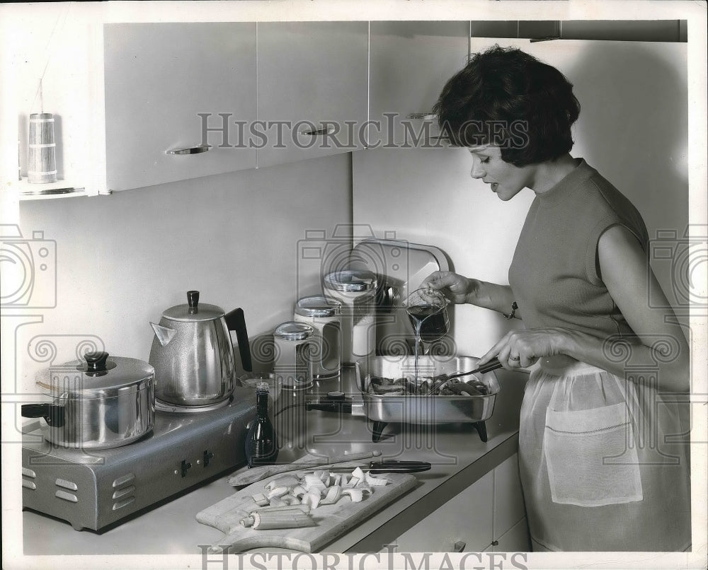 1963 A homemaker cooking in her kitchen  - Historic Images