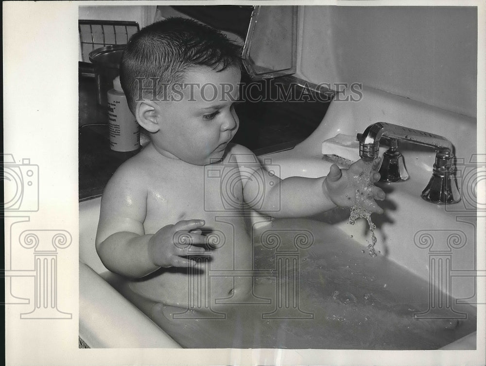 1961 Gary Richard Kaufman. age 1 gets bath in NY kitchen sink - Historic Images