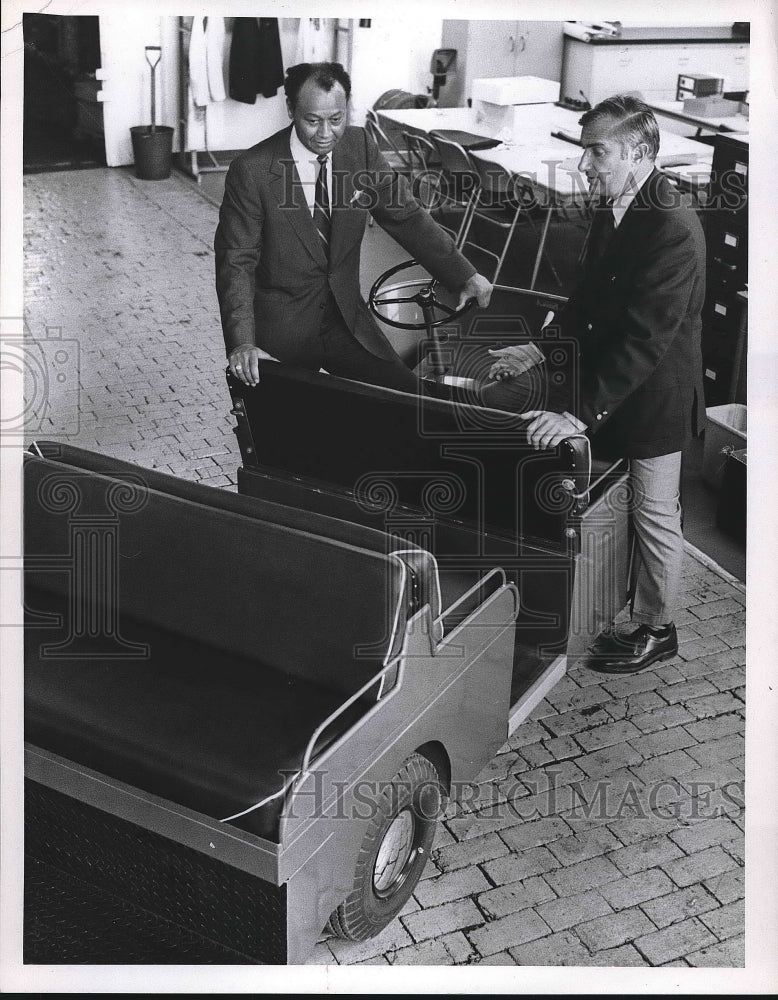 1970 Two men standing next to cart  - Historic Images