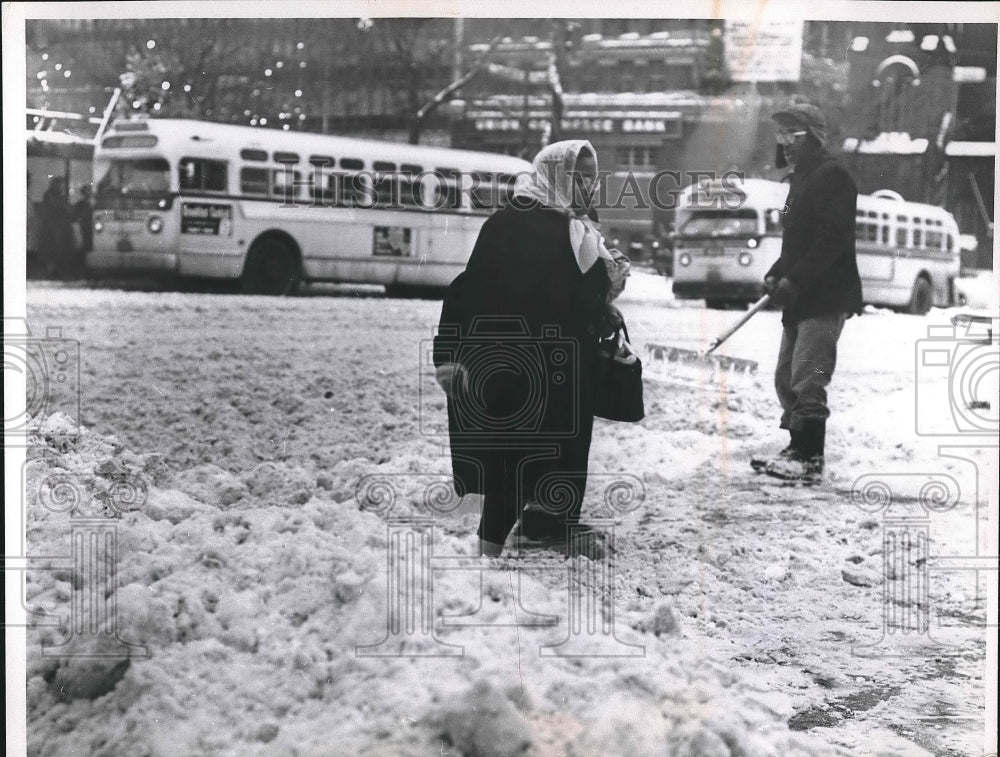 1960 Woman Walking on Snowy Streets with Snow Sweeper  - Historic Images