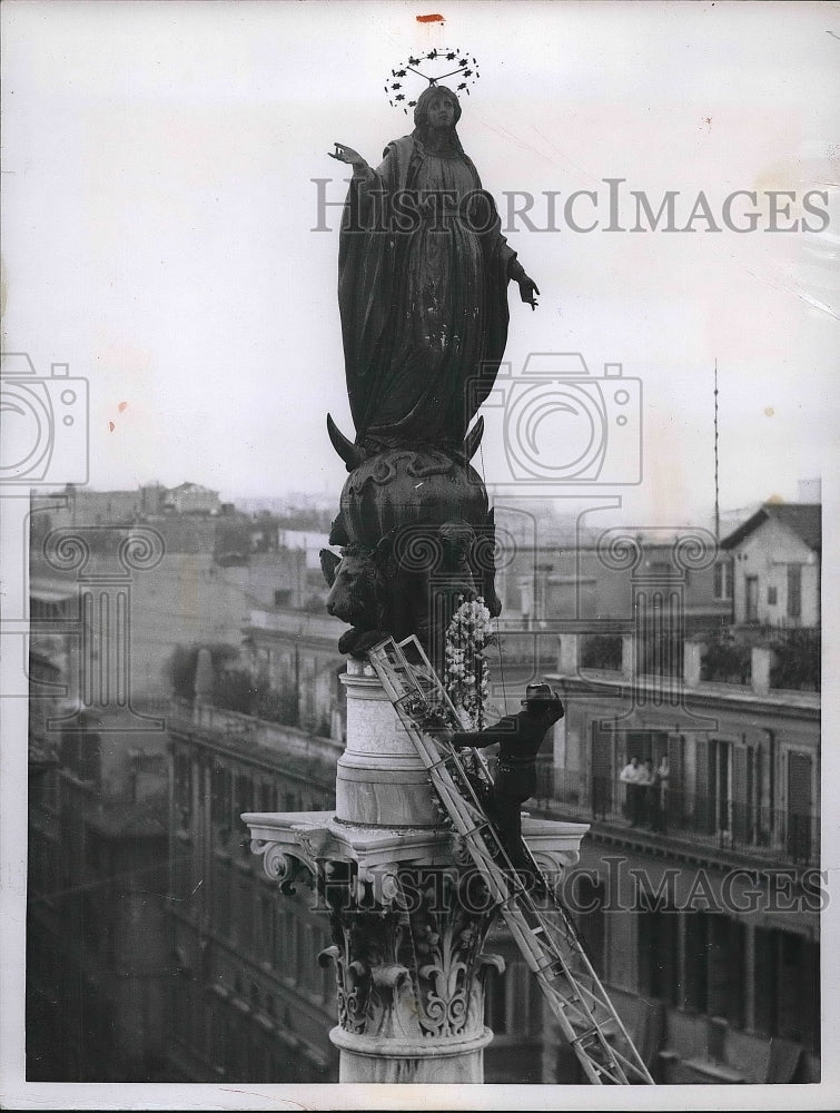 1955 Press Photo Roman fireman attends to floral decorations for the Statue of - Historic Images