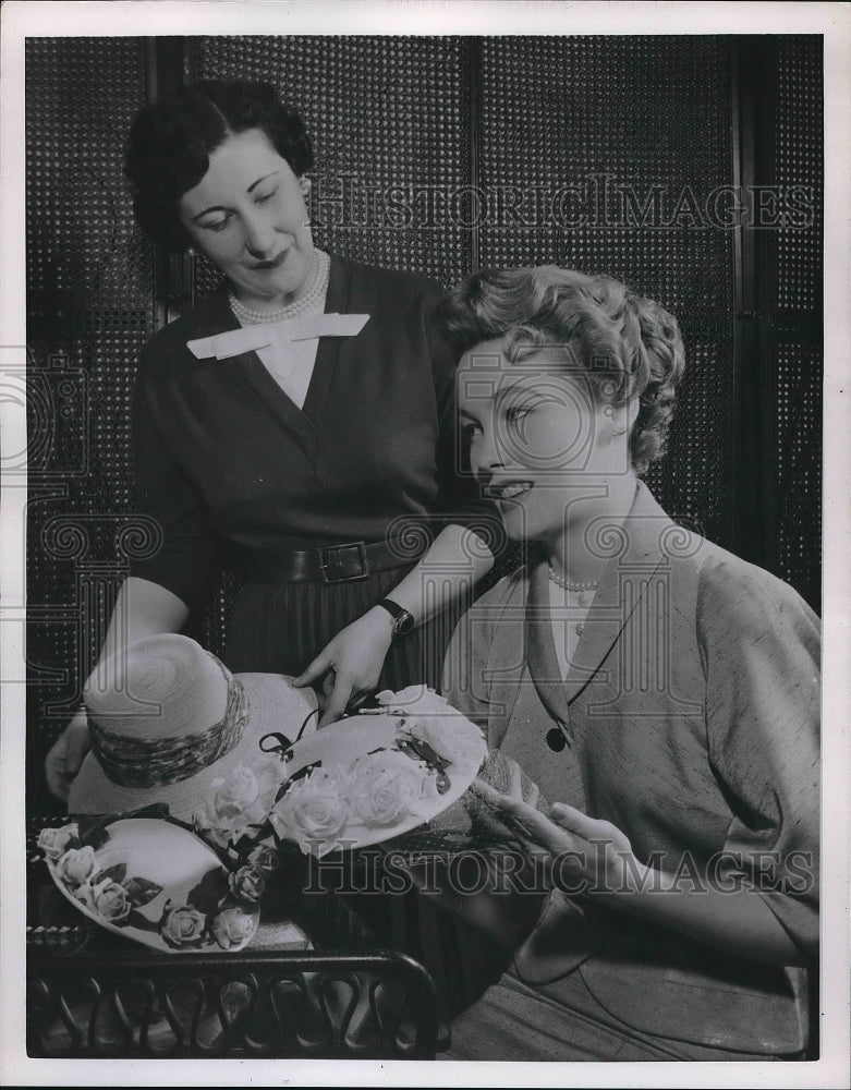 1954 Lady going through an assortment of hats in the Hat store - Historic Images