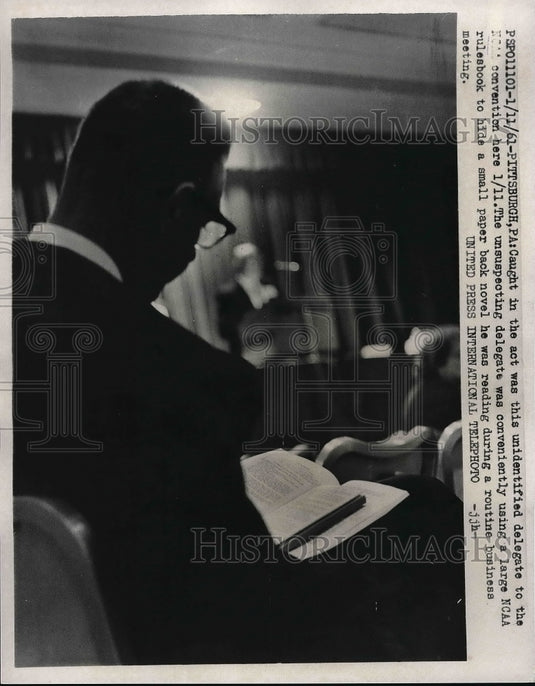 1961 Press Photo Unidentified person hiding NCAA book during a business meeting - Historic Images