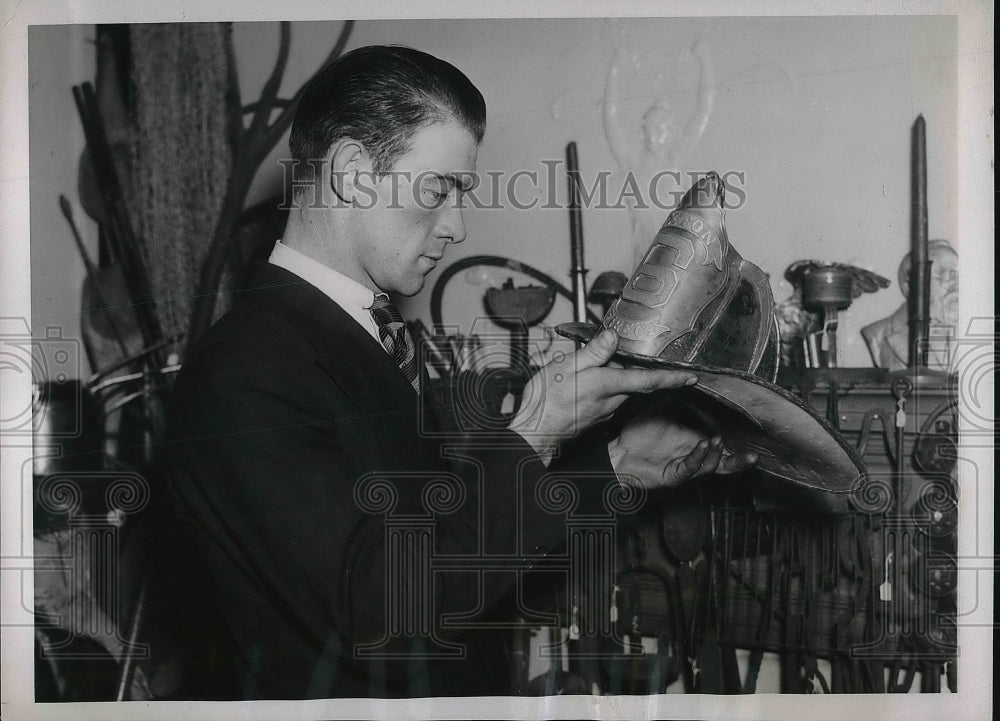 1937 Press Photo Stanley Bloom examines a fireman&#39;s hat dating back to 1859 - Historic Images