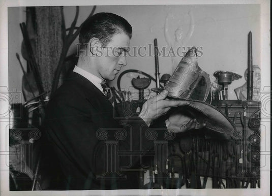 1937 Press Photo Stanley Bloom examines a fireman's hat dating back to 1859 - Historic Images