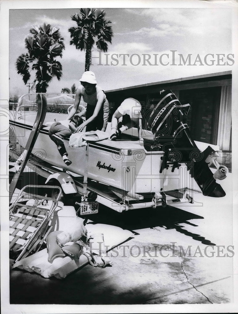 A woman helping her daughter aboard a speedboat - Historic Images