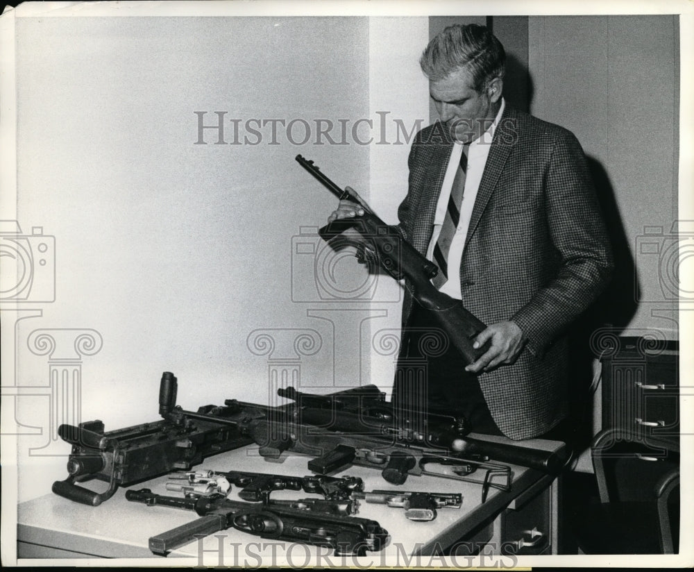 1969 Press Photo Federal Agent Paul Hankins looks over military weapons - Historic Images