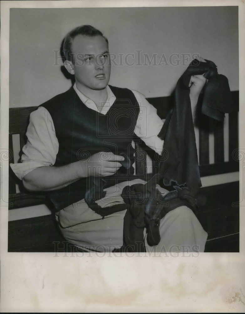 1952 Press Photo Ralph Warnecke Sitting On Bench Holding Torn Garments-Historic Images