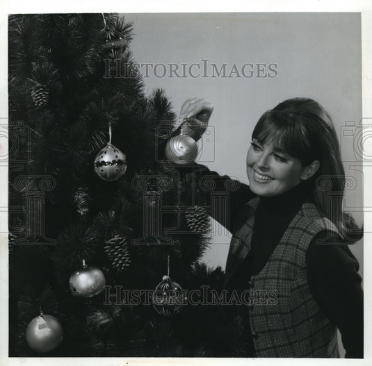 1967 A woman hanging ornaments on an Xmas tree-Historic Images