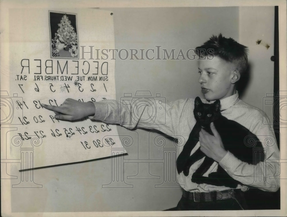 1935 Press Photo James Wihebrink pointing to an illustration while holding cat-Historic Images